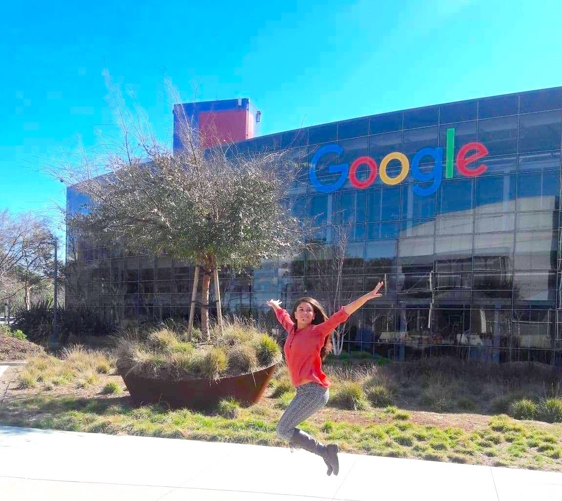 Ayleen jumping in front of the Google campus building